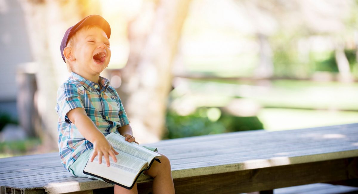 Kid laughing holding the Bible